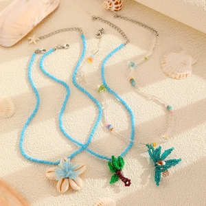 Close-up of bohemian beaded necklaces with shell, palm tree, and dragonfly charms