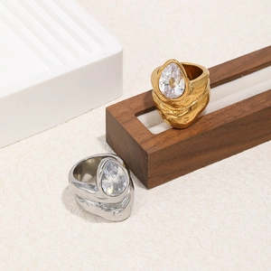 Gros plan de bagues en or et argent avec zircon goutte et texture martelée sur bois