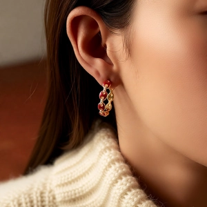Detailed close-up of 18k gold plated hoop earring with red enamel and pavé zircons
