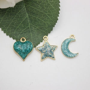 Close-up of heart, star and moon DIY charms with blue glitter and gold metal edges