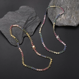 Detailed macro shot of gold and silver heart-shaped rainbow tennis necklaces on stones