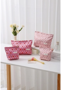 Detail view of various canvas cosmetic bags with heart patterns and metallic zipper closure