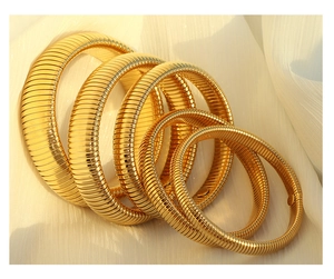 Detail showing five assorted gold Tubogas snake chain bracelets on white silk fabric