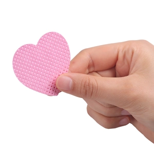 Close-up of a hand holding a pink heart-shaped textured eyelash glue cleaning wipe