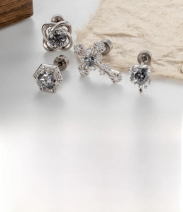 Detail of silver titanium heart and cross cartilage studs with dark grey zircon crystals