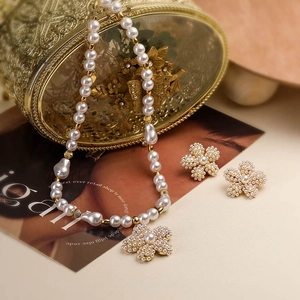 Detail of white pearl necklace with floral pendant and matching earrings in gold setting