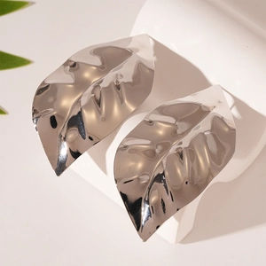 Macro detail of large silver leaf earrings with a polished metallic mirror finish