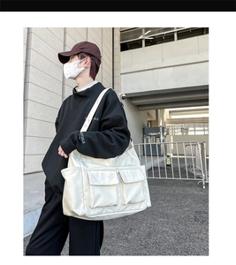 Detail shot of a white large canvas crossbody bag with dual utility pockets for women