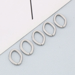 Five silver stainless steel oval twisted open rings on light blue background