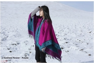 Detail of bohemian paisley shawl in purple and turquoise with fringe edges in snow