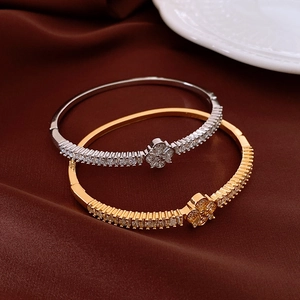 Dettaglio di bracciali a fiori in oro e argento con zirconi su seta rosso scuro