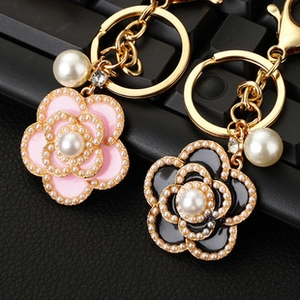 Macro shot of camellia flower keychains with pink and black enamel, pearls and crystals