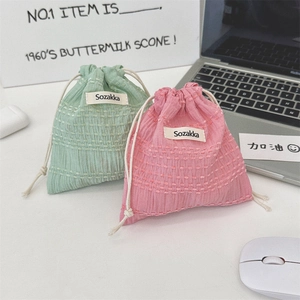 Detailed view of seersucker drawstring pouches in pink and green with textured fabric
