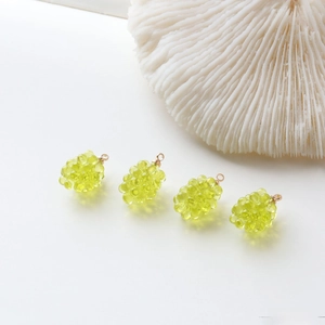 Close-up of four mini green grape resin charms with gold rings for DIY jewelry