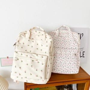 Detail view of floral canvas backpacks with rose patterns and front zipper pockets