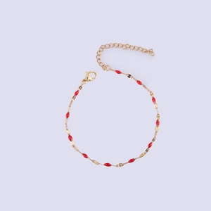 Detail of gold lip chain bracelet featuring red enamel beads and adjustable lobster clasp