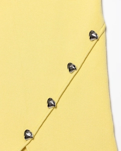 Macro detail of high-density yellow knit fabric with silver heart-shaped metal buttons