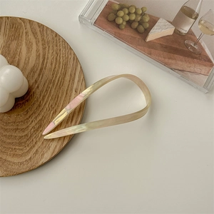 Detail of U-shaped acetate hair fork with iridescent pearlescent finish in soft pink