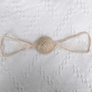 Macro shot of handmade crochet knit nose ornament on a white textured background