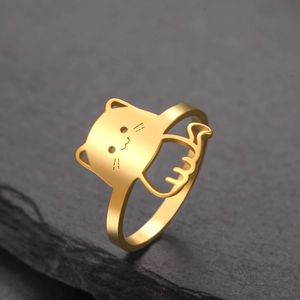 Close-up of golden cat-shaped minimalist ring on dark textured stone background