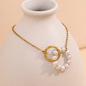 Detailed shot of double-loop gold link chain with white pearls on a ceramic vase