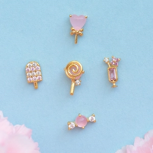 Macro detail of the ice cream and candy themed earrings with pink zircons and gold plating