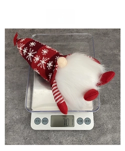 Close-up of a 70.1g glowing Christmas gnome gnome plush on a digital weight scale