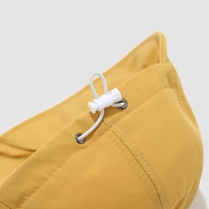 Close-up of yellow duck hat showing ripstop fabric texture and white elastic drawstring