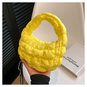 Close-up of bright yellow quilted cloud bag with puffy fabric handle and textured finish