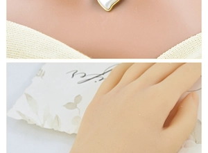 Detail of a gold-plated heart pendant with mother-of-pearl inlay worn on a neck