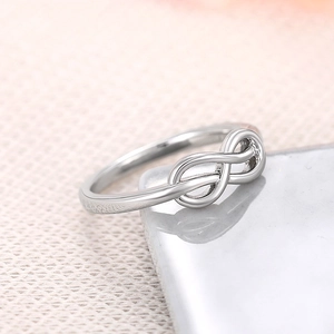 Macro-opname van gepolijste zilveren infinity ring op marmer met een roze achtergrond