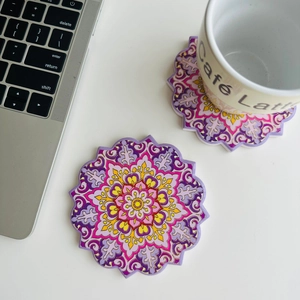 Detail of round mandala ceramic coasters with gold foil trim and a white coffee mug
