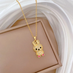 Close-up of a gold bunny necklace with sparkling stones on a white silk background