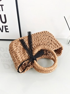 Handwoven straw tote bag in tan finish featuring a black lace bow for beach vacations