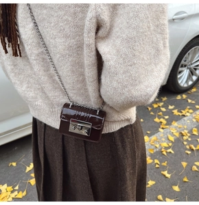 Close-up of a mini dark brown patent leather crossbody bag with a silver metal chain