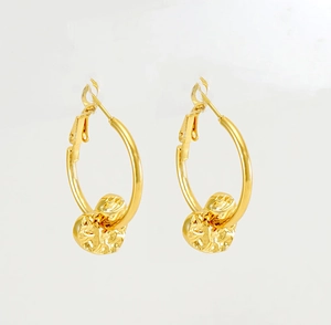 Close-up of 18K gold star earrings with irregular hammered texture on a light background