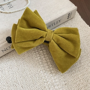 Detail of velvet bow hair clip in mustard yellow with soft flocking texture and clip