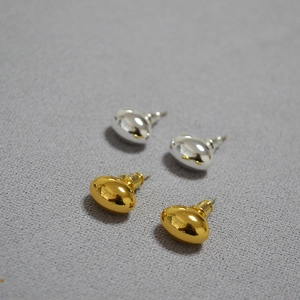 Macro shot of gold and silver bean stud earrings with high-polished mirror finish texture