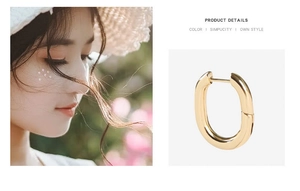 Detailed close-up of golden U-shaped oval hoop earrings worn by a female model