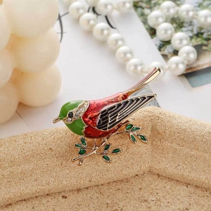 Close-up of colorful enamel bird brooch on golden branch with sparkling rhinestones