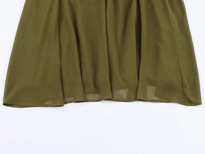 Detailed close-up of dark green chiffon dress hem with pleated texture and fine stitching