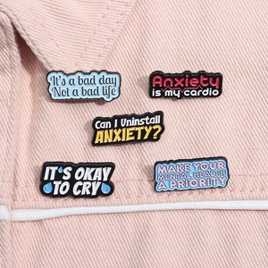 Set of five colorful mental health enamel pins pinned on pink denim fabric