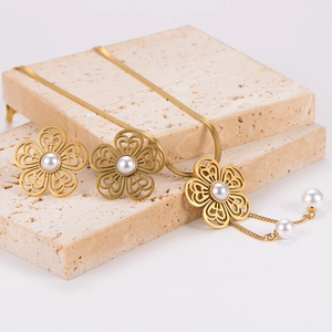 Golden stainless steel floral necklace and earring set with pearls on stone slabs