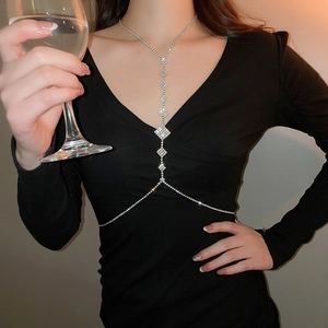 Close-up of elegant silver rhinestone body chain with diamond patterns on a black dress
