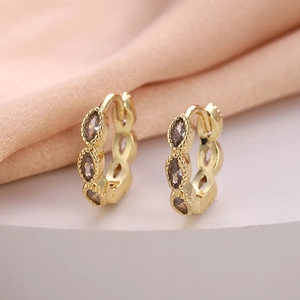 Macro detail of gold huggie earrings featuring marquise-cut marquise-cut zircon stones