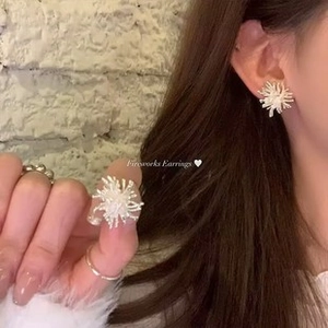 Close-up of elegant firework style earrings featuring a white radial tassel design