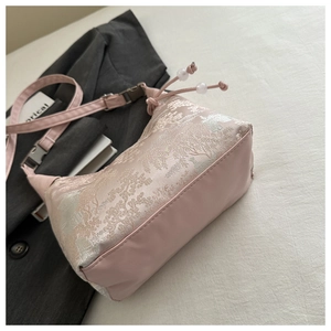Detail of pink embroidered silk handbag with floral patterns and pearl drawstring closure