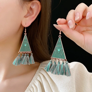 Detail showing green fringe tassel triangle earrings with turquoise stone worn by model