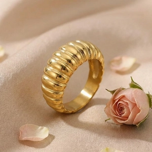 Macro view of gold-tone croissant ring with ribbed texture on elegant silk background