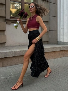 Detail of high-waisted black maxi skirt featuring 3D floral texture and high side slit